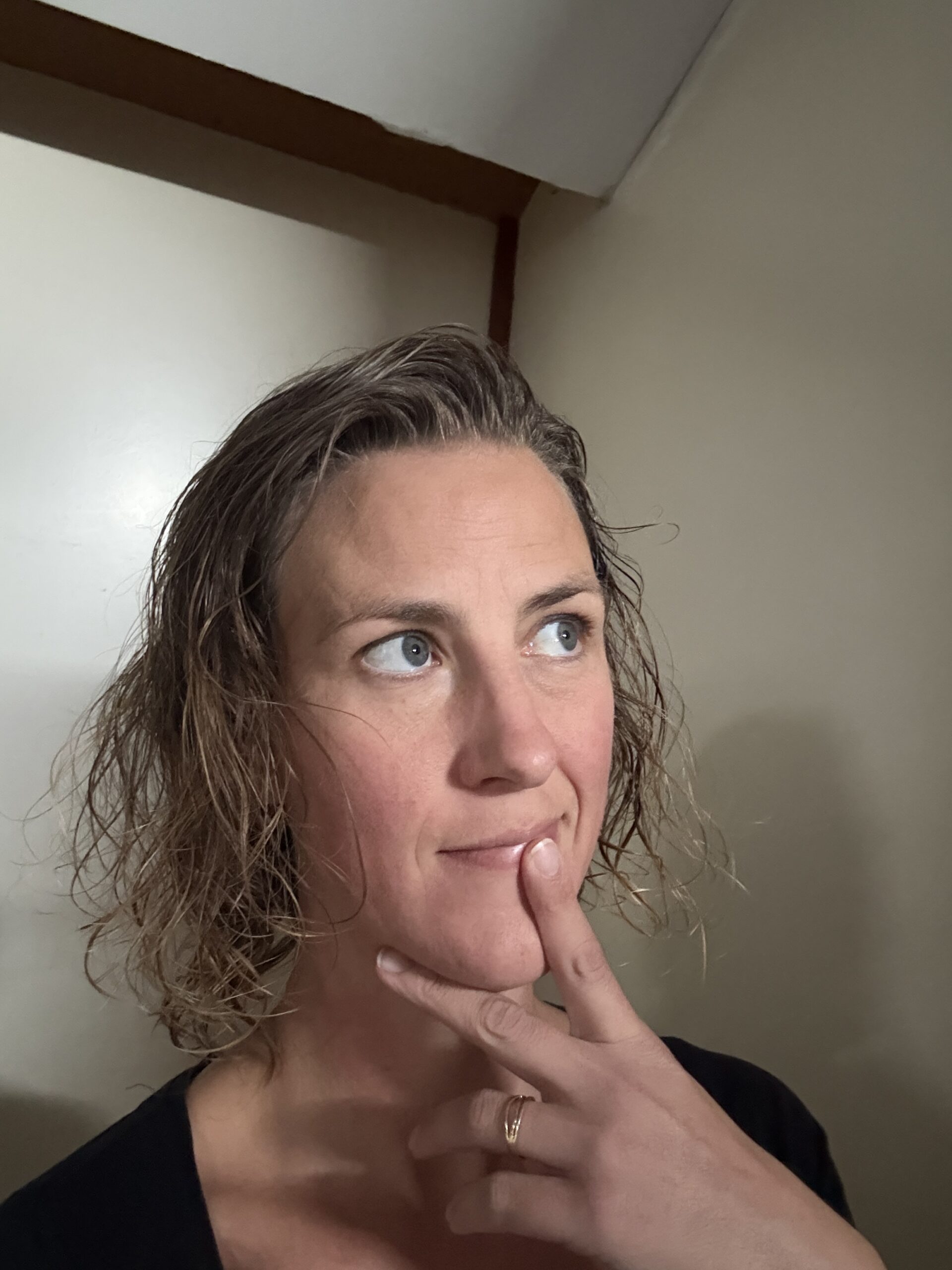 Linda kijkt peinzend omhoog met haar hand tegen haar kin.